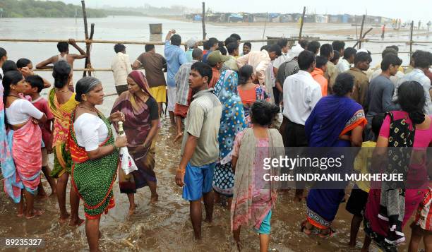 Shantytown residents on Versova beach, stand behind a temporary barricade on high ground in ankle deep sea water as they wait for the seasons's...