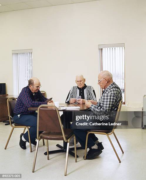 three mature men sitting at table playing cards - retirement card stock pictures, royalty-free photos & images