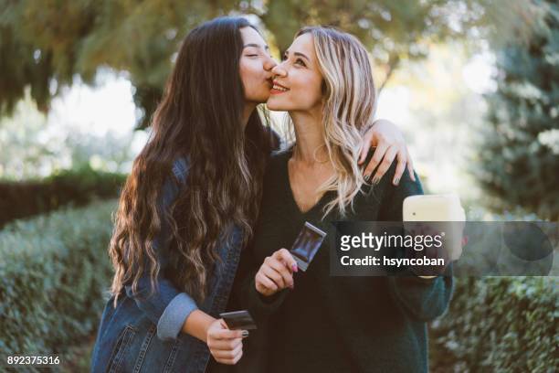 instant photo of girl kissing friend on the cheek - introducing girlfriend stock pictures, royalty-free photos & images