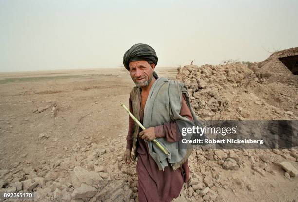 An Afghan shepherd steps over a shattered stone wall in an area bombed by US aircraft November 1, 2001 in Chowkar Karez, Kandahar Province,...