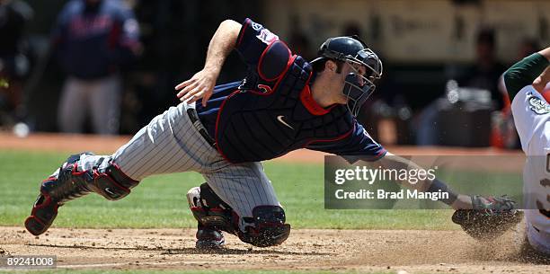 Joe Mauer of the Minnesota Twins makes a late tag as Oakland Athletics base runner Jack Cust slides home safely during the game at the...