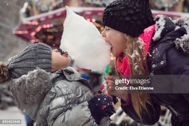 two children sharing cotton candy at a german christmas market in the snow - bobble hat stock pictures, royalty-free photos & images