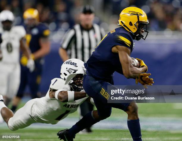 Wide receiver Jon'Vea Johnson of the Toledo Rockets is tackled by cornerback Alvin Davis of the Akron Zips during the first half at Ford Field on...
