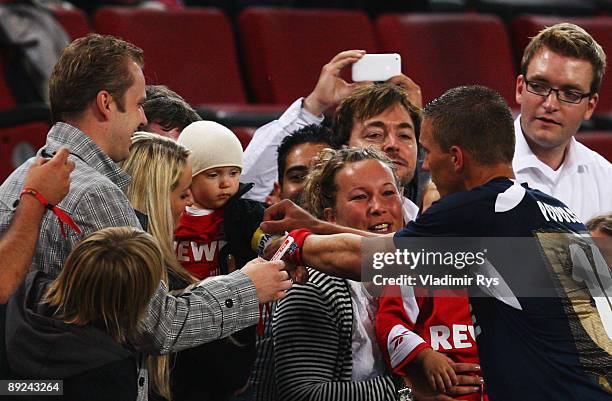 Lukas Podolski of Koeln puts on a captain arm band to his child held by his girlfriend Monika Puchalski after the pre-season friendly match between...