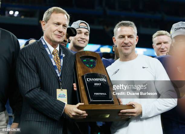 Dr. Jon Steinbrecher, commissioner of the Mid-American Conference, presents the MAC Championship trophy to head coach Jason Candle of the Toledo...