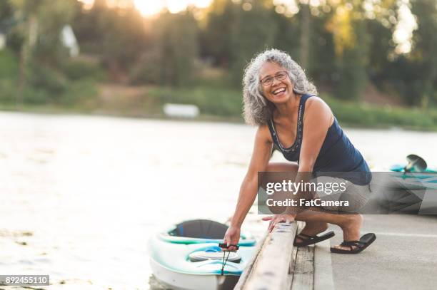 een prachtige etnische oudere vrouw bereidt om te gaan kajakken - active seniors stockfoto's en -beelden