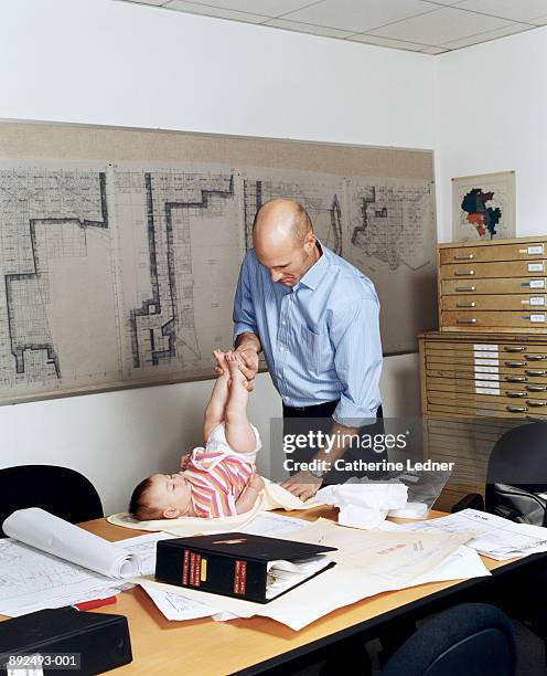 businessman changing daughter's diaper on conference room table - crazy dad stock pictures, royalty-free photos & images