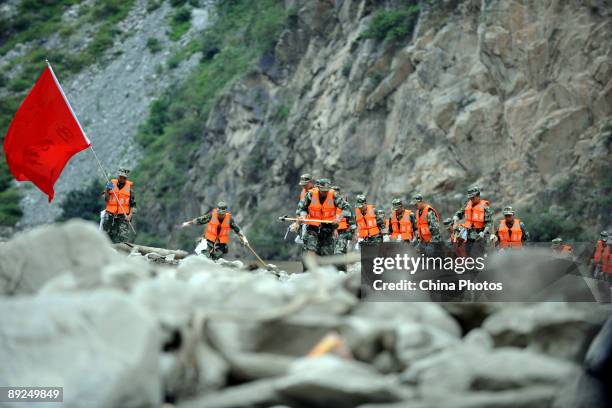 Paramilitary policemen walk among mud-rock flow for a rescue mission after a landslide on July 25, 2009 in Kangding County of Ganzi Tibetan...