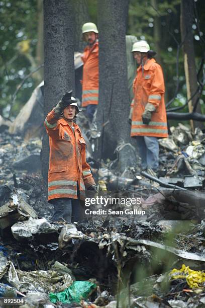 German firefighters stand among the wreckage of a DHL Boeing 757 cargo plane July 2, 2002 in a forest near the town of Taisersdorf, Germany. The...