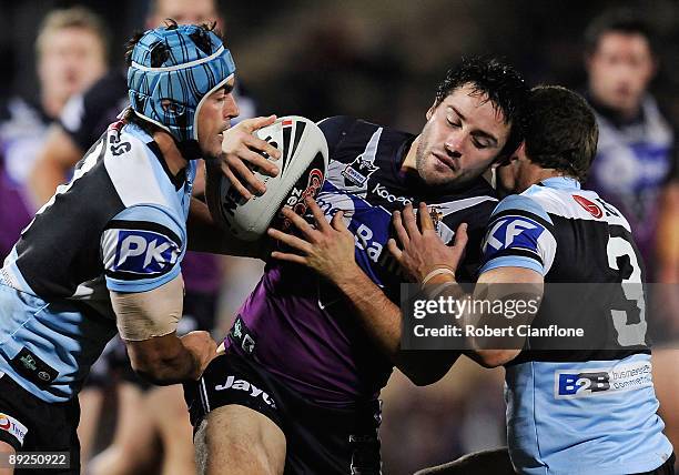 Scott Porter and Ben Pomeroy of the Sharks tackle Cooper Cronk of the Storm during the round 20 NRL match between the Melbourne Storm and the...