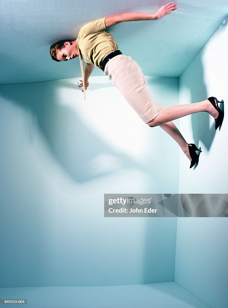 Woman holding on to walls, about to fall off room