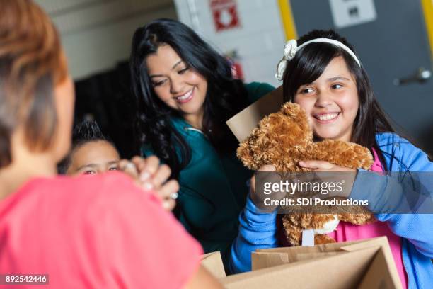 chica recibe el oso de peluche durante el evento de caridad - receiving fotografías e imágenes de stock