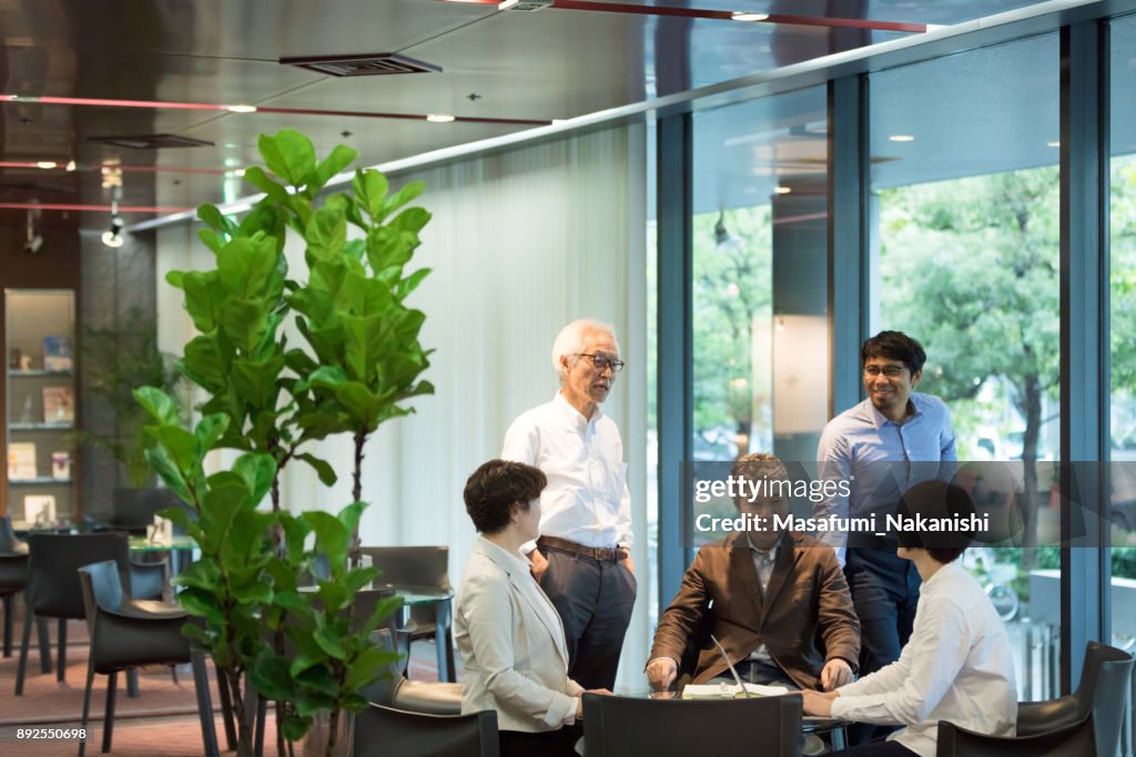 Olika ålder asiatiska business-team möts runt bordet