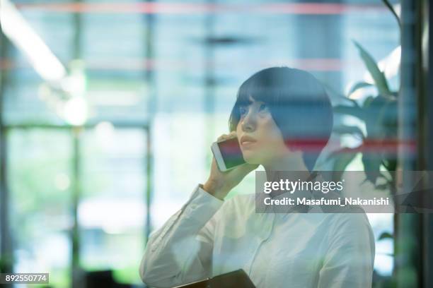 asian woman are using smartphone in office building  through the window - business woman looking through window stock pictures, royalty-free photos & images