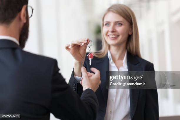 weibliche immobilienmakler geben hausschlüssel an kunden - agent and handing keys stock-fotos und bilder