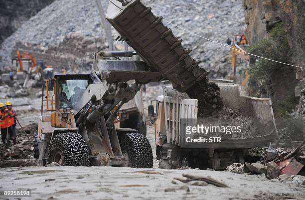 Chinese rescuers use heavy machinery to dig up the mud and rock after a rock slide in mountainous Kangding county, southwest China's Sichuan province...