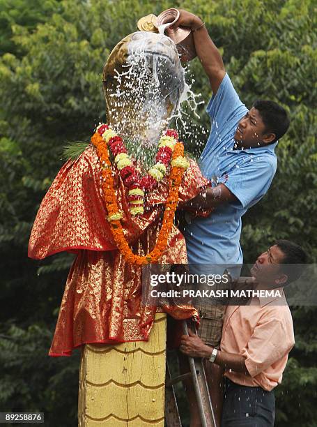 Nepalese devotee pays obeisance by pouring cow's milk over a golden statue of the Hindu snake god known as 'Nag' at Nagpokhari in Kathmandu on July...