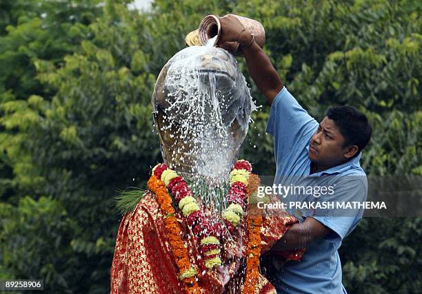 Nepalese devotee pays obeisance by pouring cow's milk over a golden statue of the Hindu snake god known as 'Nag' at Nagpokhari in Kathmandu on July...