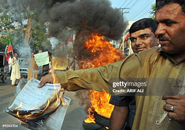 Pakistani man burns an electricity bill in protest against the electrical shortages in Lahore on July 26, 2009. Away from the killing fields between...