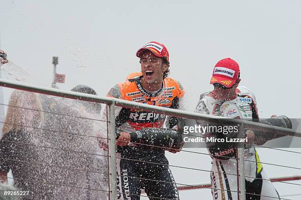 Andrea Dovizioso of Italy and Repsol Honda Team and Colin Edwards of USA and Monster Yamaha Tech 3 spray champagne and celebrate on the podium after...