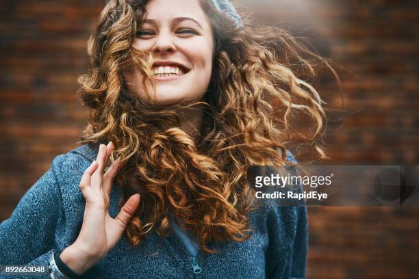 beautiful girl with winter windblown hair laughs - tossing hair facing camera woman outdoors stock pictures, royalty-free photos & images