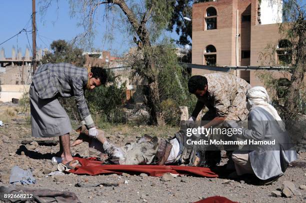 People carry a body of a prisoner after he was killed in airstrikes targeted the prison on December 13, 2017 in Sana’a, Yemen. More than 12 prisoners...