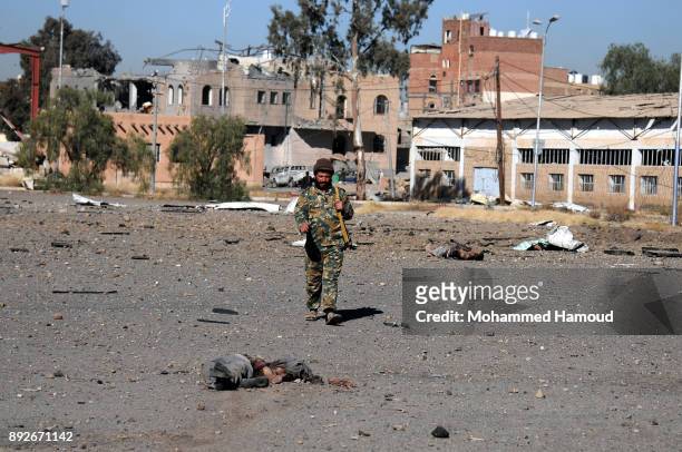 Soldier walks near a body of a prisoner after he was killed in airstrikes targeted the prison on December 13, 2017 in Sana’a, Yemen. More than 12...