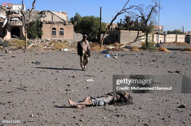 Man walks near a body of a prisoner after he was killed in airstrikes targeted the prison on December 13, 2017 in Sana’a, Yemen. More than 12...