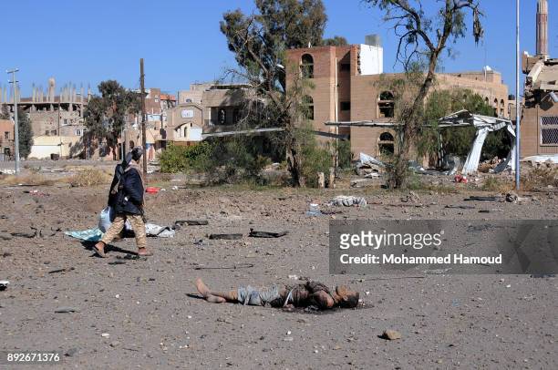 Man walks near a body of a prisoner after he was killed in airstrikes targeted the prison on December 13, 2017 in Sana’a, Yemen. More than 12...
