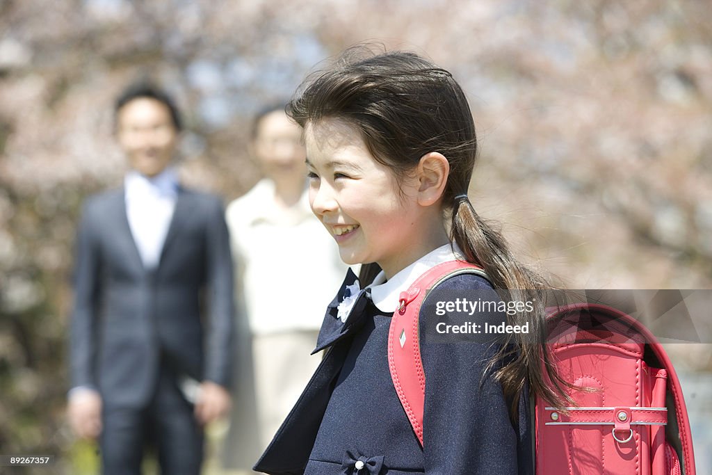 Schoolgirl (8-9) smiling, parents in background