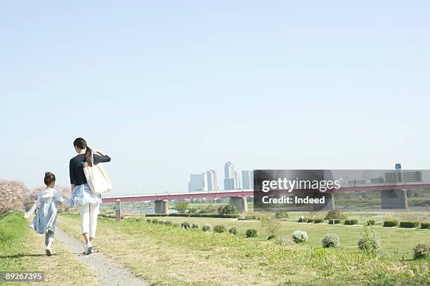 mother and daughter walking side of river - familia de dos generaciones fotografías e imágenes de stock