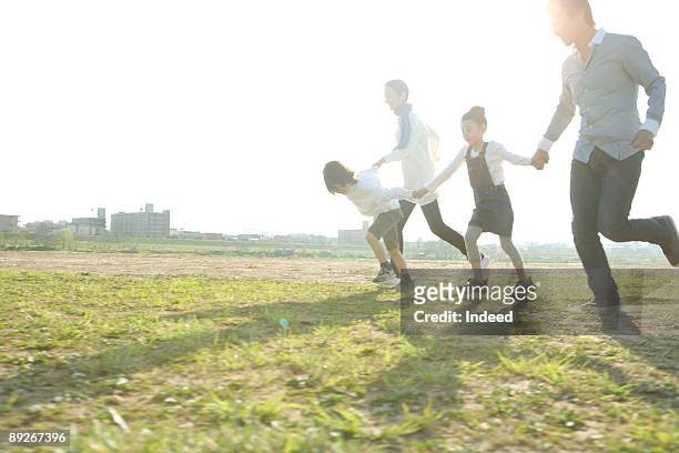 parents with two kids holding hands and running - 家族　日本人　走る ストックフォトと画像