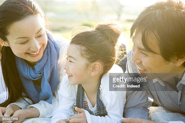 parents with girl (8-9) relaxing on mat - japanischer abstammung stock-fotos und bilder