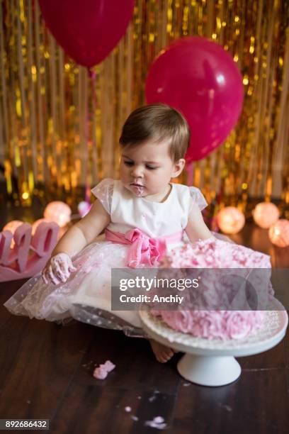 cute little baby girl celebrating her birthday with smash cake - cake smashing stock pictures, royalty-free photos & images