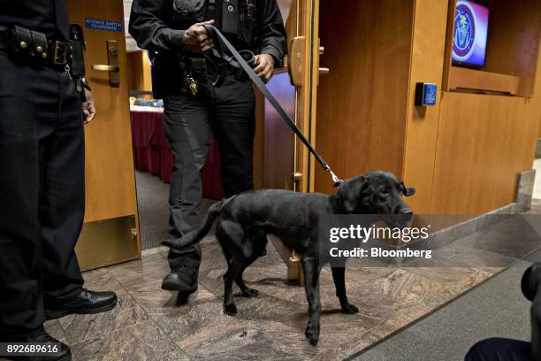 Police officer walks a bomb detection dog out of the Federal Communications Commission meeting room during an evacuation at an open commission...