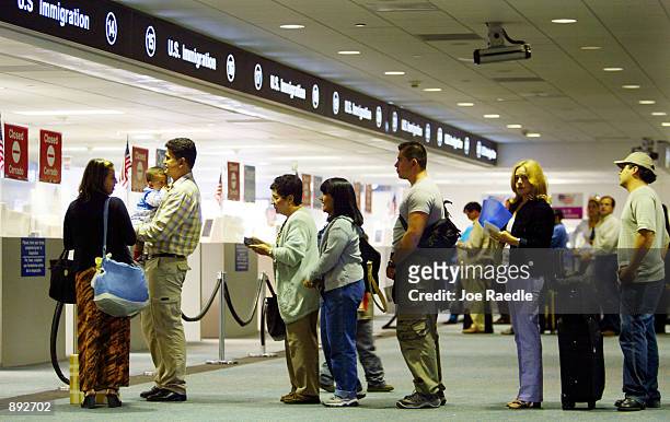 People wait in line to have their passports checked by Immigration inspectors July 2, 2002 at Miami International Airport in Miami, Forida....