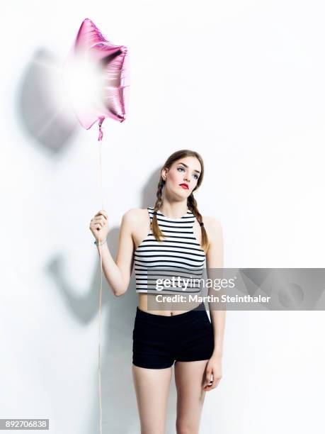 model mit hotpants und gestreiftem top hält luftballon - luftballon fotografías e imágenes de stock