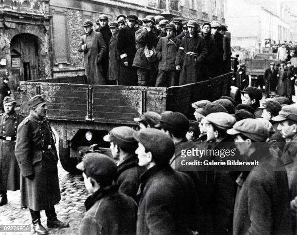 Jewish men are transported from the Warsaw Ghetto by Wehrmacht soldiers, to work on sites elsewhere, Poland, 1941.