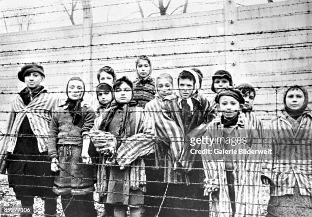 Group of child survivors behind a barbed wire fence at the Nazi concentration camp at Auschwitz-Birkenau in southern Poland, on the day of the camp’s...