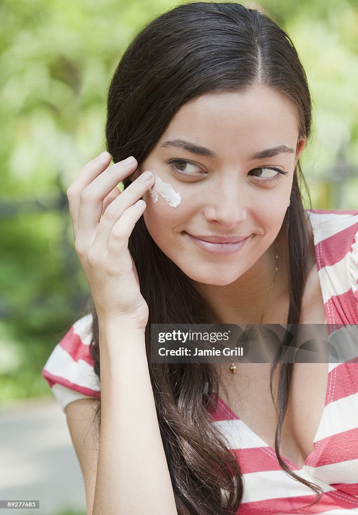 Woman Putting Suntan Lotion on Cheek