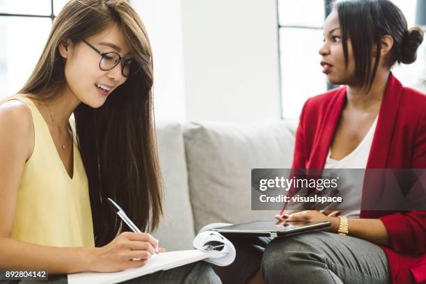 due donne che lavorano insieme discutendo - popolo eurasiatico foto e immagini stock