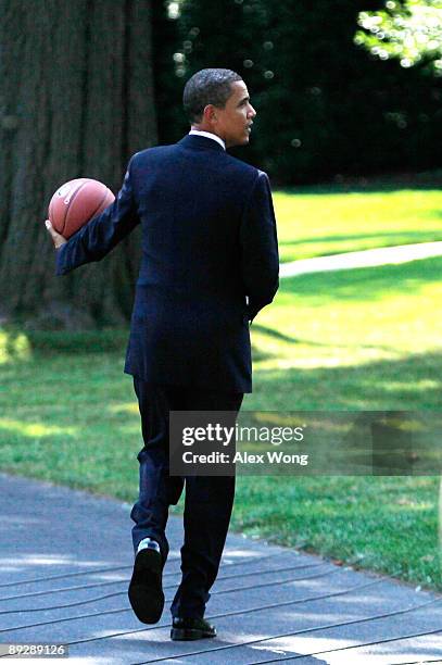 President Barack Obama holds a basketball as he walks toward the Oval Office after he hosted Detroit Shock at the South Portico of the White House...