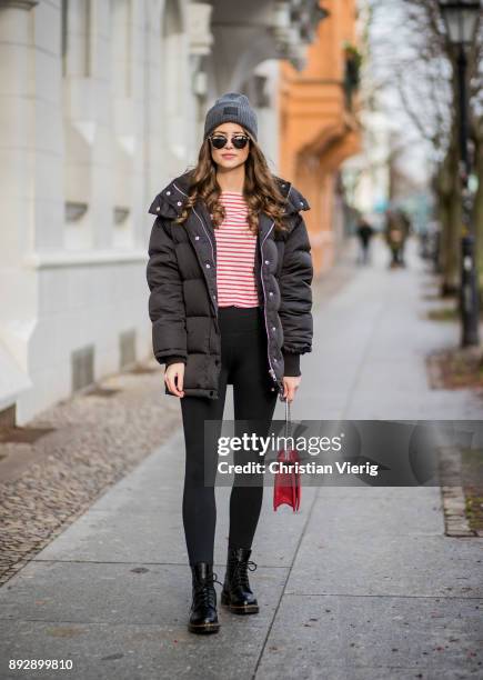 Jennifer Amanda wearing a grey wool hat from Acne, a black puffer jacket from Edited, a classic black high waist leggings from Fabletics, a red white...