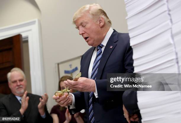 President Donald Trump holds a pair of gold colored scissors used to cut a symbolic piece of red tape during an event at the White House promoting...