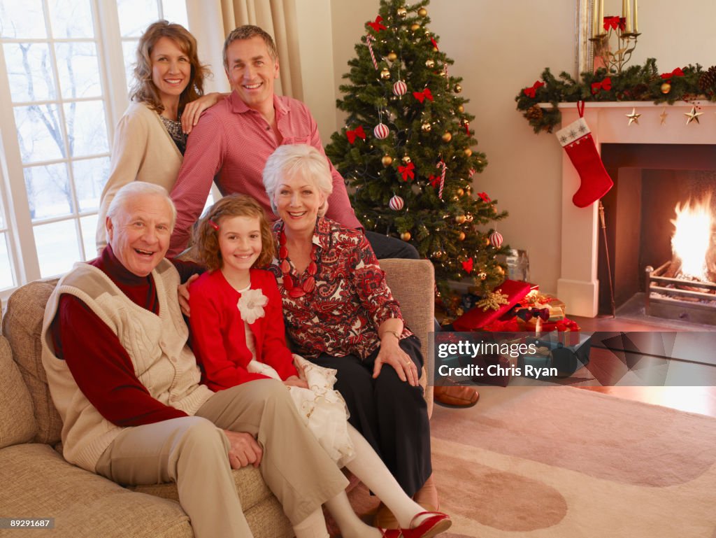 Multi-generation family sitting on sofa near Christmas tree