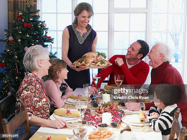 woman serving christmas turkey to multi-generation family at table - old man woman christmas stockfoto's en -beelden