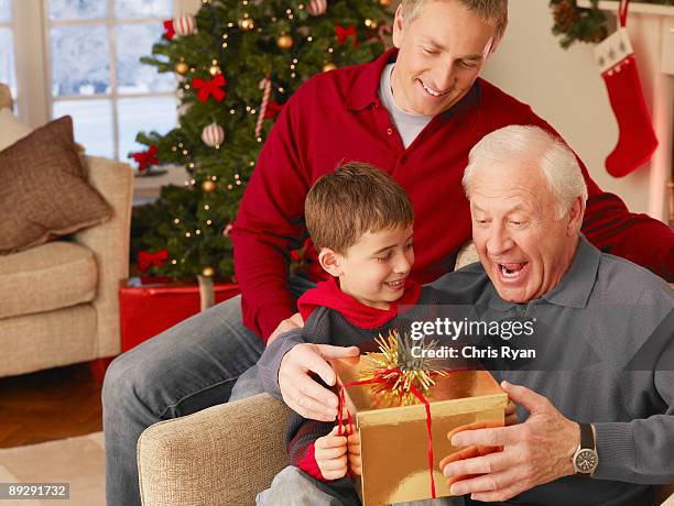 boy giving grandfather christmas gift - papa noel stockfoto's en -beelden