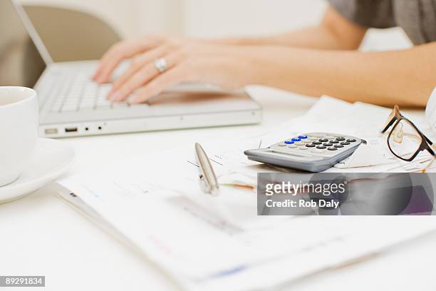 mujer escribiendo en computadora portátil, cerca de las facturas y calculadora - calculadora fotografías e imágenes de stock