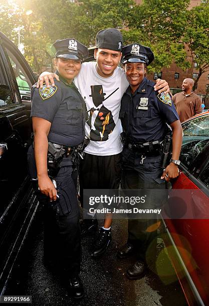 Chris Brown poses with NYPD officers before playing a basketball game in Manahttan on July 27, 2009 in New York City.