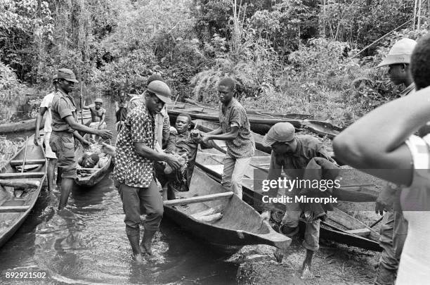 Biafran soldiers and helpers seen here carrying an injured comrade onto a canoe to cross the river during the Biafra conflict, 11th June 1968.